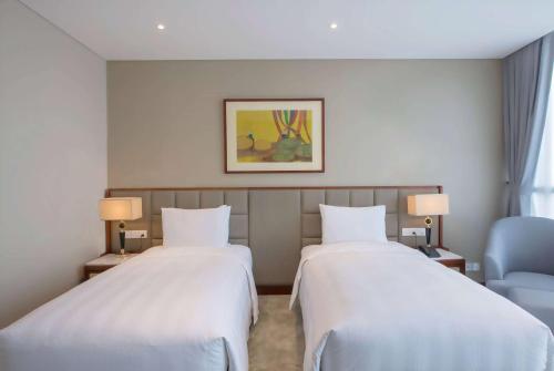 a hotel room with two beds and a chair at Wyndham Garden Hanoi in Hanoi