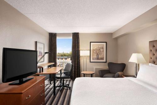 a hotel room with a bed and a flat screen tv at Royal Hotel Regina, Trademark Collection by Wyndham in Regina