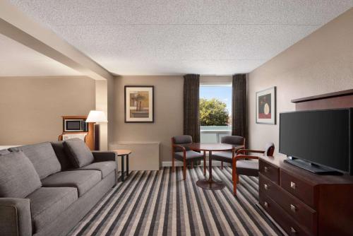 a living room with a couch and a television at Royal Hotel Regina, Trademark Collection by Wyndham in Regina
