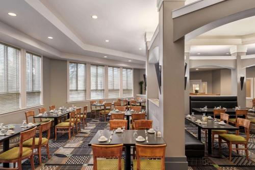 a dining room with tables and chairs and windows at Royal Hotel Regina, Trademark Collection by Wyndham in Regina