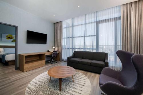 a living room with a couch and a television and a bed at Wingate by Wyndham Long Island City in Queens