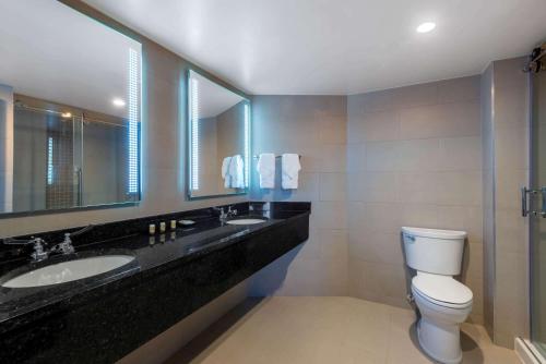 a bathroom with a toilet and two sinks and a mirror at Wyndham Lancaster Resort and Convention Center in Lancaster