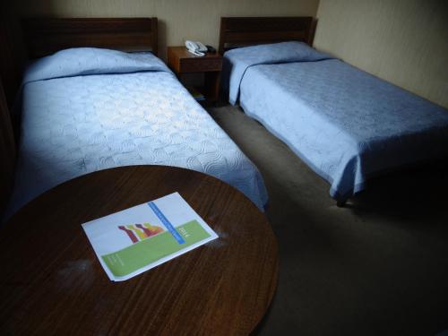 a book on a table in a room with two beds at Hotel Antupiren in Puerto Montt