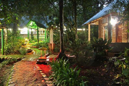 a garden at night with a house in the background at Hosteria El Paraiso de las Orquideas in Archidona