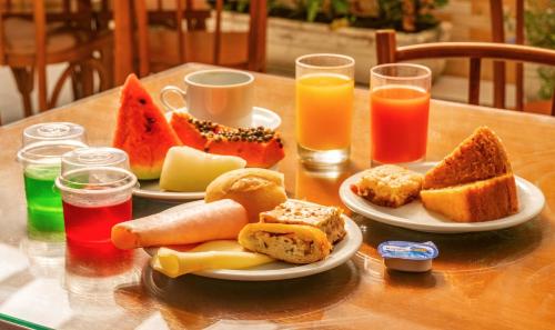a table with plates of food and glasses of juice at UPG Hotel in Ubatuba
