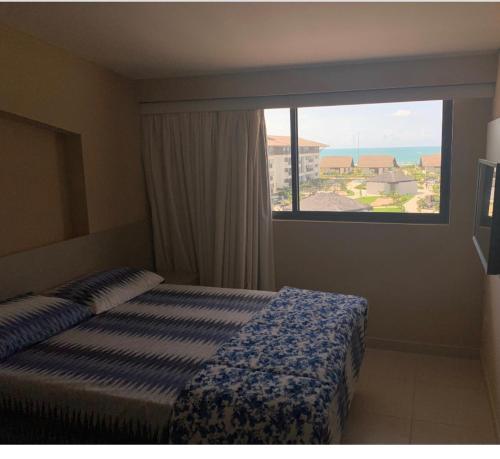Cette chambre comprend un lit et une grande fenêtre. dans l'établissement Cupe Beach Living Porto de Galinhas, à Porto de Galinhas