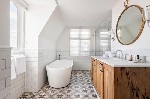 a white bathroom with a tub and a sink at The National Hotel in Fremantle