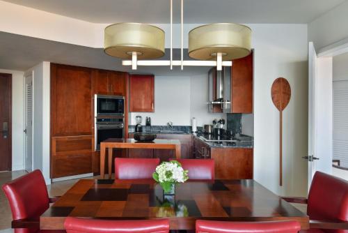 a kitchen with a wooden table and red chairs at Ka Laʻi Waikiki Beach, LXR Hotels & Resorts in Honolulu