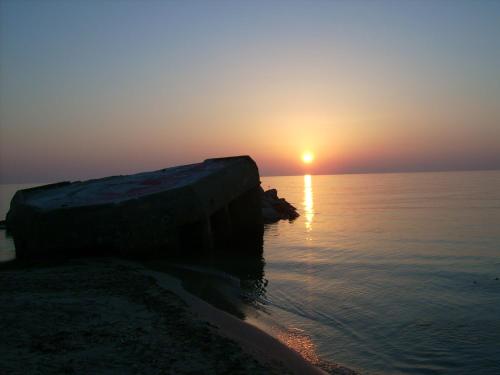 a sunset over the ocean with a rock in the water at Dar Baaziz in Sousse