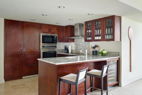 a kitchen with wooden cabinets and a counter with stools at Ka Laʻi Waikiki Beach, LXR Hotels & Resorts in Honolulu