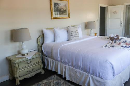 a bedroom with a white bed and a nightstand with two lamps at La Villa de Adelina in Ensenada