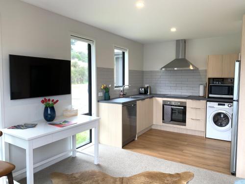 a kitchen with a white table and a tv at Hillside Studio in Queenstown