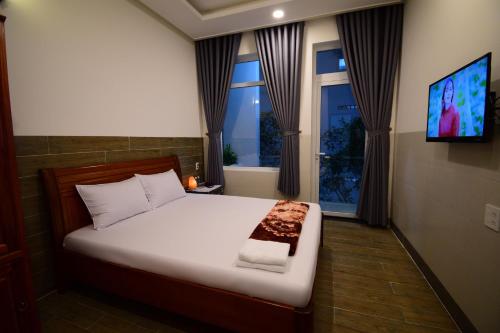 a bedroom with a bed and a tv and windows at Nhà nghỉ Hùng Hoa in Phan Thiet