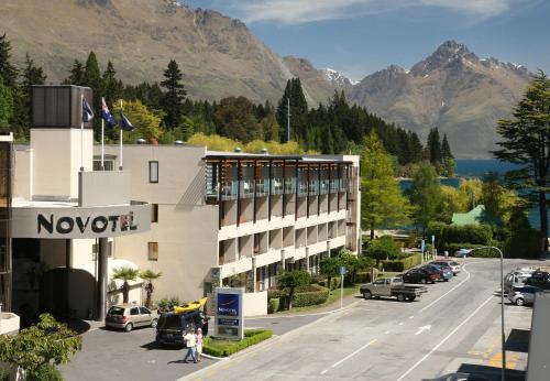 a view of a hotel with mountains in the background at Novotel Queenstown Lakeside in Queenstown