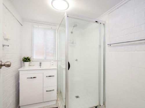 a white bathroom with a shower and a sink at Comfy Studio with Idyllic Yard in Great Location in Terrigal