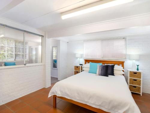 a white bedroom with a bed and a window at Comfy Studio with Idyllic Yard in Great Location in Terrigal