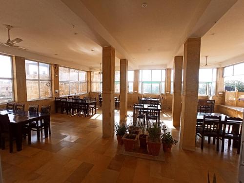 ein Esszimmer mit Tischen, Stühlen und Fenstern in der Unterkunft Hotel Royal Haveli in Jaisalmer