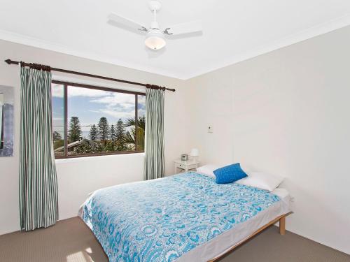 1 dormitorio con cama y ventana grande en Family Beachside Getaway with BBQ and Patio en Terrigal