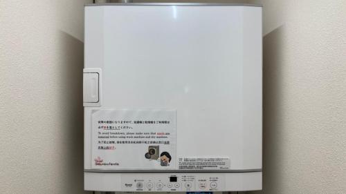 a white refrigerator with a sign on the wall at Hotel Sakurano Familia Nago in Nago