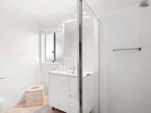 a white bathroom with a shower and a sink at Spacious Beachside Townhouse with Large Balcony in Terrigal