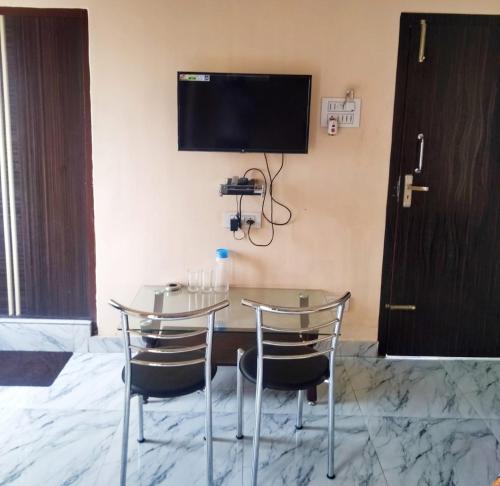 a table with two chairs and a television on a wall at Woodland Lodge and Restaurant in Guwahati