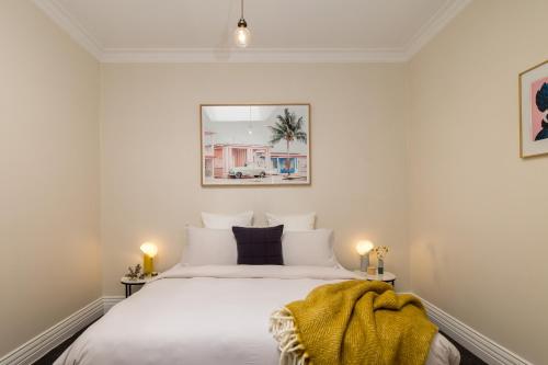 een slaapkamer met een wit bed met een deken erop bij Central Geelong West Cottage in Geelong West