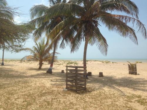 a beach with two palm trees and a wooden structure at El Remanso del Santuario in Camarones