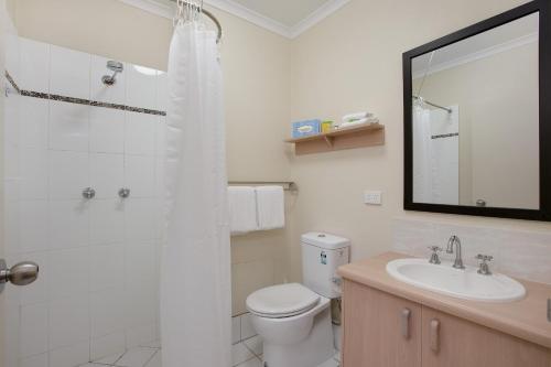 a bathroom with a shower and a toilet and a sink at Cairns City Sheridan Motel in Cairns