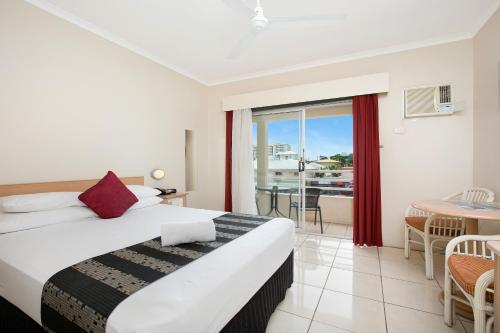 Cairns City Sheridan Motel في كيرنز: غرفه فندقيه بسرير وشرفه