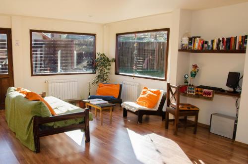 a living room with a couch and chairs and windows at Hostería Los Gnomos in El Calafate