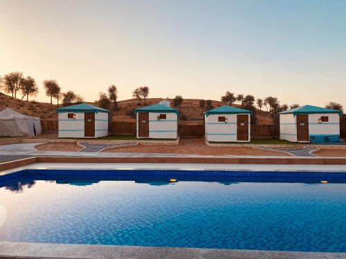 a row of outbuildings with a swimming pool in front of a resort at Bedouin Oasis Desert Camp- Ras Al Khaimah in Ras al Khaimah