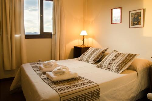 1 dormitorio con 2 toallas en una cama con ventana en Hostería Los Gnomos en El Calafate
