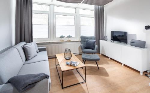 a living room with a couch and a tv and a table at Strandloft Drei Norderney in Norderney