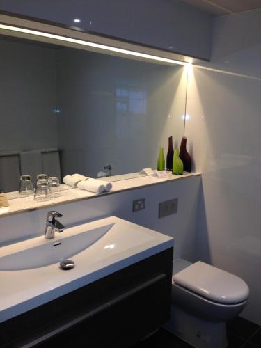 a bathroom with a sink and a toilet and a mirror at Lakes Hotel in Adelaide