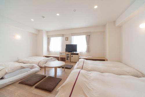 a bedroom with two beds and a table and a tv at Okayama View Hotel in Okayama
