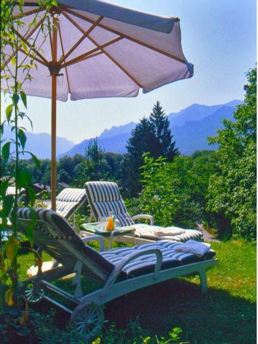 a chair and an umbrella and a table and chairs at Landhotel Sonnleiten in Bad Reichenhall