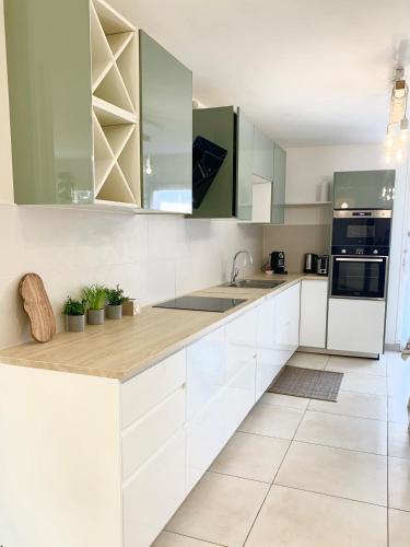 - une cuisine blanche avec des placards verts et blancs dans l'établissement Havre de paix moderne et spacieux, Évry-Courcouronnes