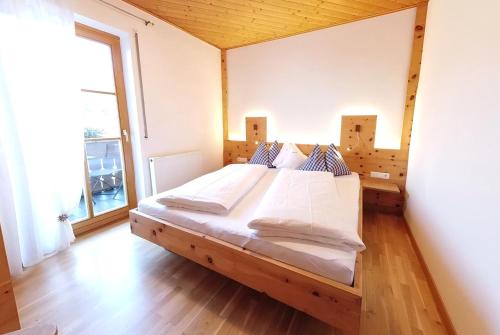 een groot bed in een kamer met een groot raam bij Appartements Grumserhof in Merano