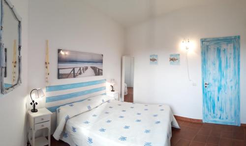 a white bedroom with a bed and a blue door at Le case di Stella Maris in Palau