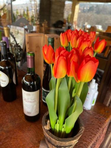 a vase filled with red flowers on a counter with bottles of wine at Vila Prezident in Sremski Karlovci