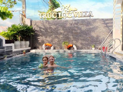 two children swimming in a swimming pool at a hotel at Truc Loc Villa in Hoi An