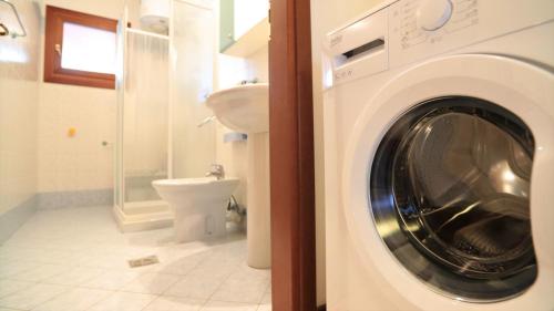 a washing machine in a bathroom with a toilet at Residence Leopardi - Gemini in Bibione