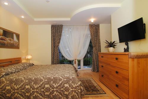 a bedroom with a bed and a dresser with a television at Saulės Krantas in Palanga