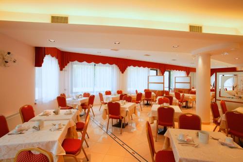 Hotel La Torretta في كاستيل سان بييترو تيرمي: غرفة طعام مع طاولات بيضاء وكراسي حمراء
