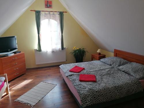 una camera da letto con un letto con due asciugamani rossi di Park Vendégház a Herend