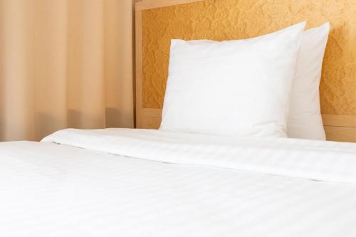a white bed with a pillow on top of it at Hotel Kolumbs in Liepāja