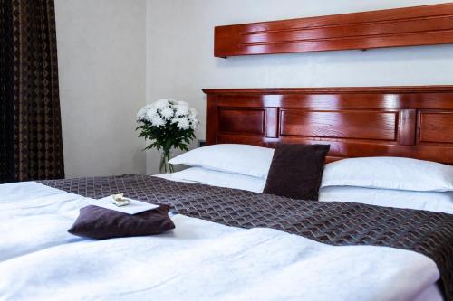 a bedroom with two beds with white sheets and a wooden headboard at Vila Prezident in Sremski Karlovci
