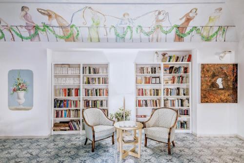 een woonkamer met 2 stoelen, een tafel en boekenplanken bij Hotel Terme Oriente - Beach & SPA in Ischia