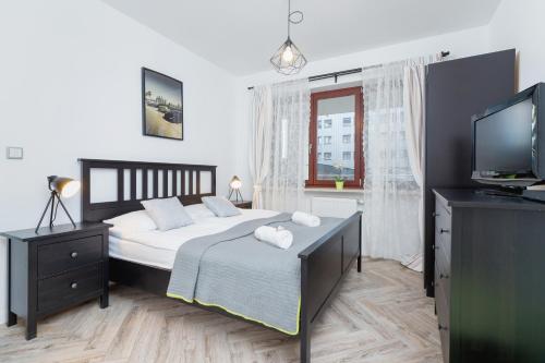 a bedroom with a large bed and a television at Premium Apartment Ludwinowska Kraków by Renters in Kraków