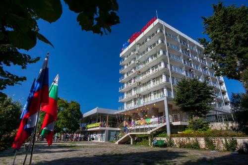un edificio alto con banderas delante en Hotel Coop - Kiten, en Kiten